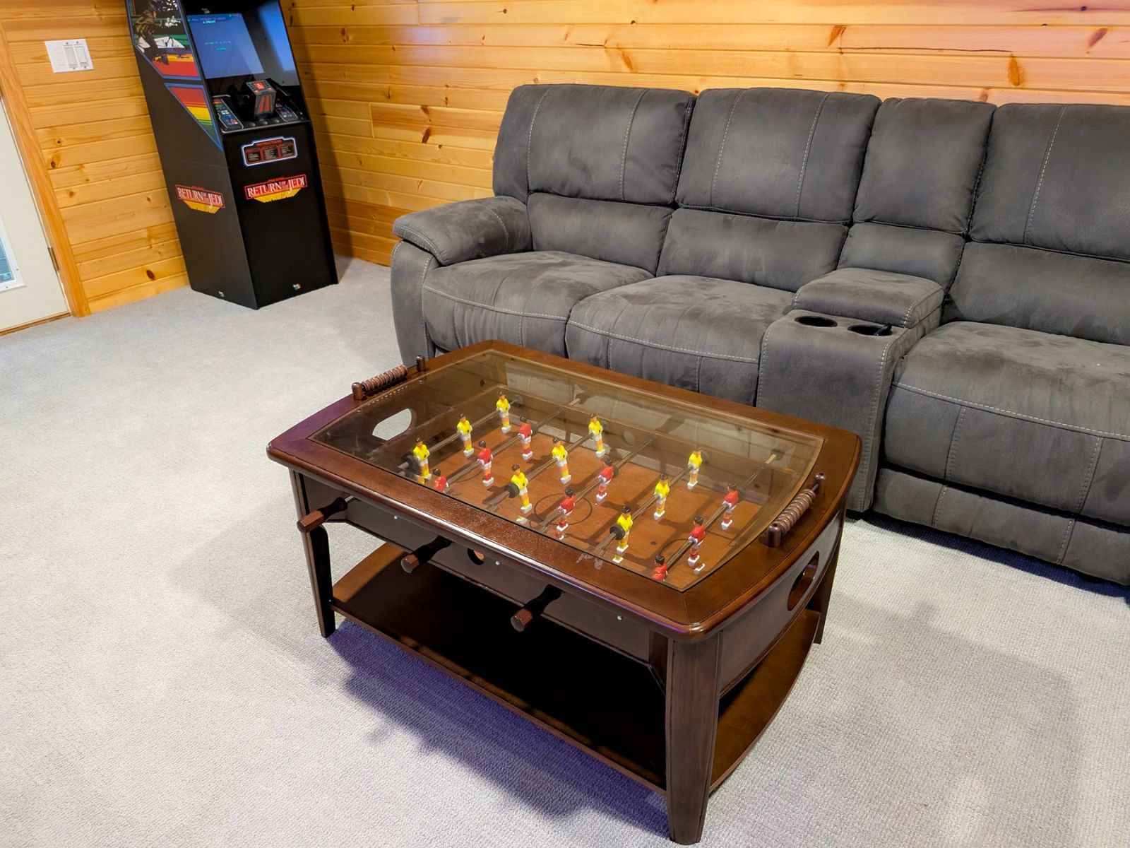 Game room detail showing the foosball table, reclining sofa, and arcade cabinet