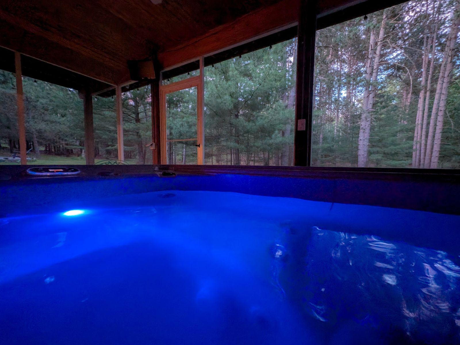 The illuminated hot tub on the property's screened porch
